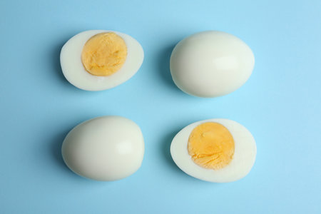 Fresh hard boiled chicken eggs on light blue background, flat lay