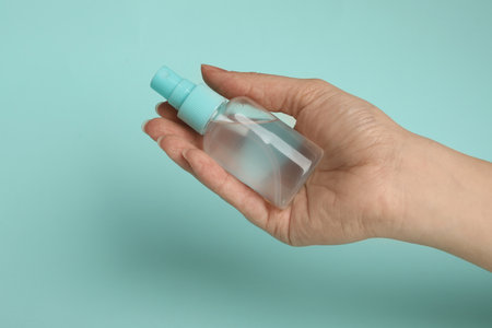 Woman holding antiseptic spray on light blue background, closeupの写真素材