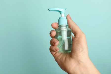 Woman holding antiseptic gel on light blue background, closeupの写真素材