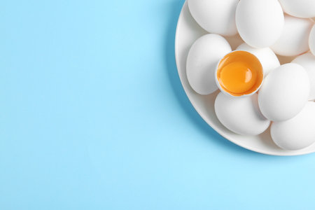 Fresh raw chicken eggs on light blue background, top view. Space for textの写真素材