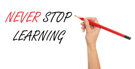 Woman writing phrase NEVER STOP LEARNING on white background, closeup. banner designの写真素材