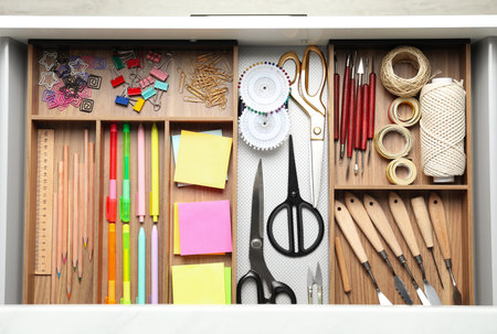 Sewing accessories and stationery in open desk drawer, top viewの写真素材