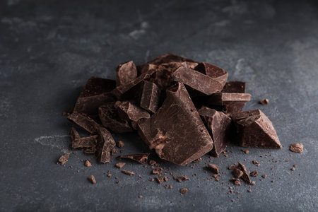 Pieces of tasty dark chocolate on gray table, closeup