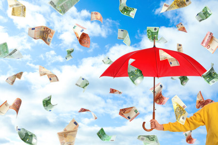 Woman holding umbrella under money rain and blue sky on background, closeupの写真素材