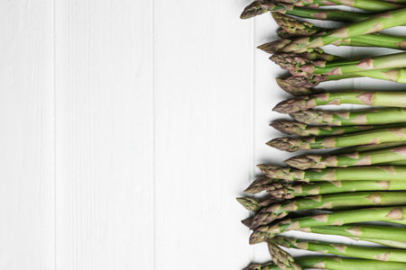 Fresh raw asparagus on white table, flat lay. Space for textの写真素材