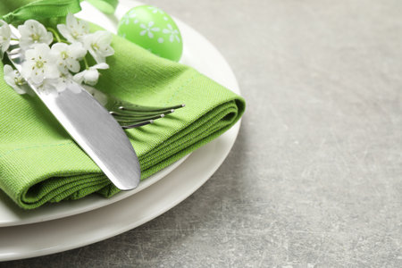Festive Easter table setting with floral decor on gray background, closeup