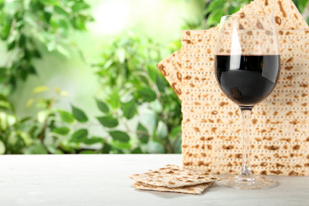 Traditional Matzos and glass of wine on white wooden table, space for text. Pesach (Passover) celebrationの写真素材