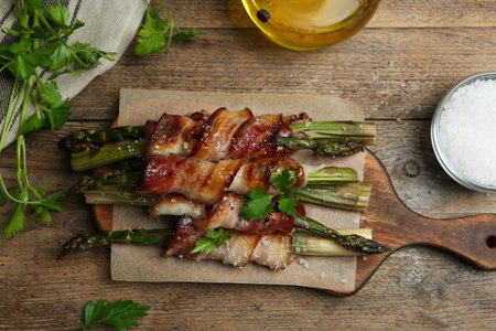 Oven baked asparagus wrapped with bacon on wooden table, flat layの写真素材
