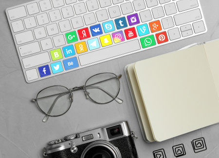 MYKOLAIV, UKRAINE - APRIL 30, 2020: Computer keyboard with social media apps logotypes on gray table, flat layのeditorial素材