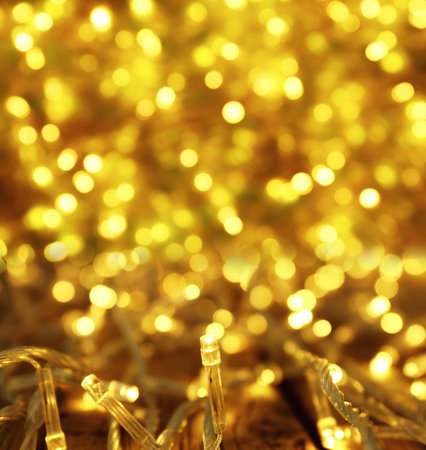 Glowing gold Christmas lights on table, closeup view. bokeh effect