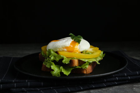 Delicious poached egg sandwich served on black plateの写真素材