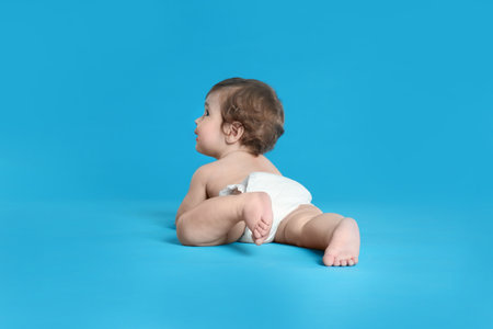 Cute little baby in diaper on light blue backgroundの写真素材