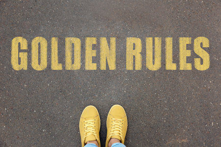 Woman standing near phrase GOLDEN RULES on asphalt, top viewの写真素材