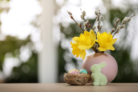 Festive composition with Easter eggs in decorative nest on table against blurred window, space for...