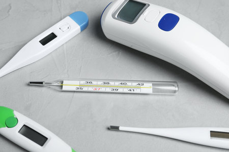 Mercury, non-contact infrared and digital thermometers on light grey stone background