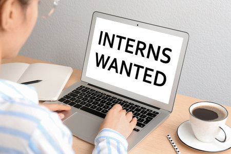 Woman with modern laptop at wooden table, closeup. Interns wantedの写真素材