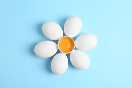 Fresh raw chicken eggs on light blue background, flat layの写真素材