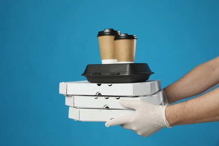Courier in protective gloves holding order on blue background, closeup.の写真素材