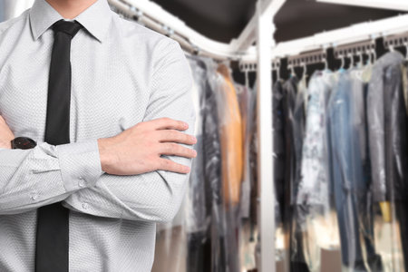 Businessman and garment conveyor at dry-cleaner's, closeup. Space for textの写真素材