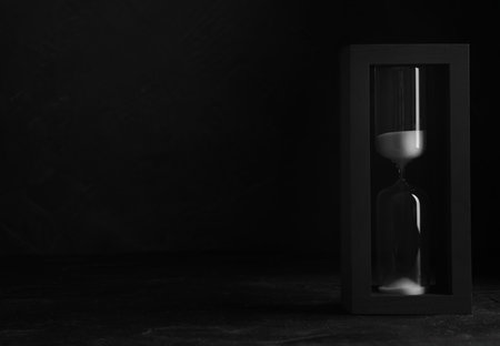Sandglass on table against black background, space for text. Pareto principle conceptの写真素材