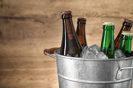 Metal bucket with beer and ice cubes on wooden background. Space for textの写真素材