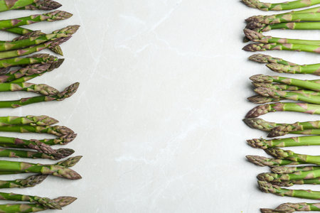 Fresh raw asparagus on light gray marble table, flat lay. Space for textの写真素材