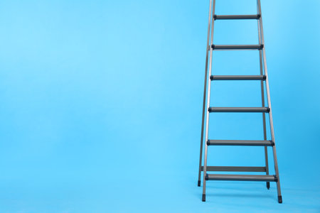 Metal stepladder on light blue background. Space for textの写真素材
