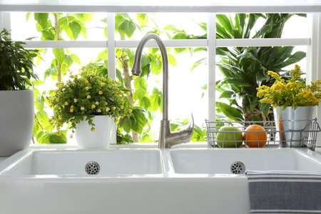 Beautiful white sink near window in modern kitchenの写真素材
