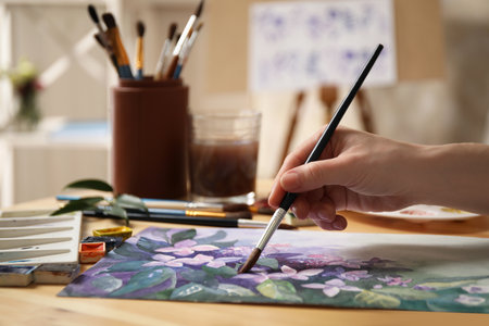 Woman painting flowers with watercolor at table in workshop, closeupの写真素材