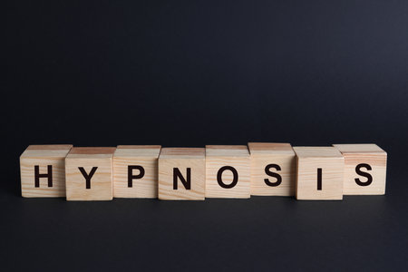 Wooden blocks with word HYPNOSIS on black backgroundの写真素材