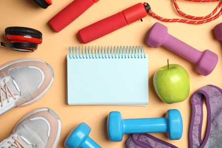 Flat lay composition with fitness equipment, notebook and apple on orange background, space for textの写真素材
