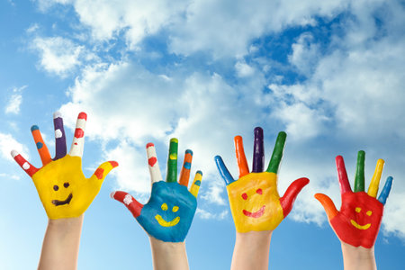 school holidays. Children with painted palms and blue beautiful sky on background, closeupの写真素材