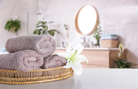 Fresh towels and lily flower on wooden table in bathroom. Space for textの写真素材
