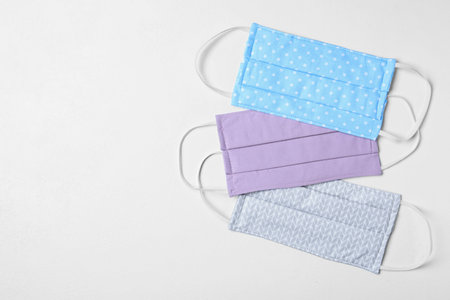 Homemade protective masks on white background, flat lay with space for text. Sewing ideas