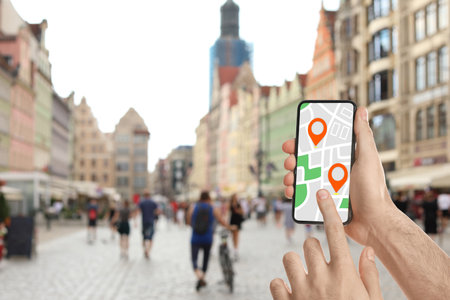 Man searching location with smartphone in city, closeup. Space for text