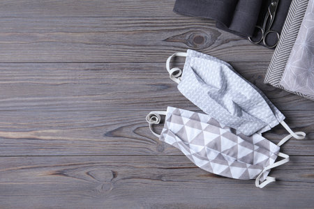 Protective masks, fabric and scissors on wooden background, flat lay with space for text. Sewing ideasの写真素材