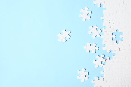 Blank white puzzle pieces on light blue background, flat lay. Space for textの写真素材
