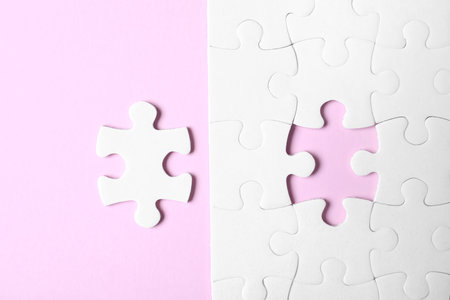 White puzzle with separated piece on pink background, flat layの写真素材
