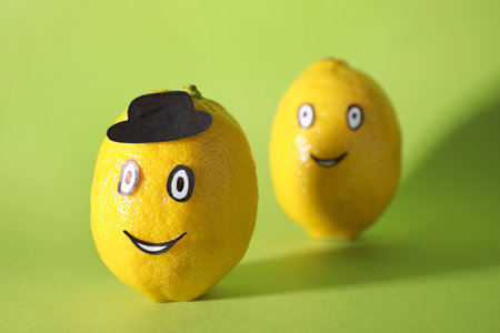 Lemons with drawn faces on green background. concept of jealousyの写真素材