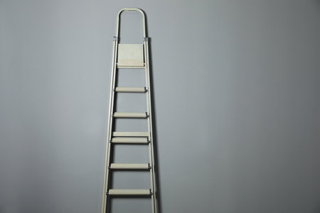 Metal stepladder on gray background. Space for text