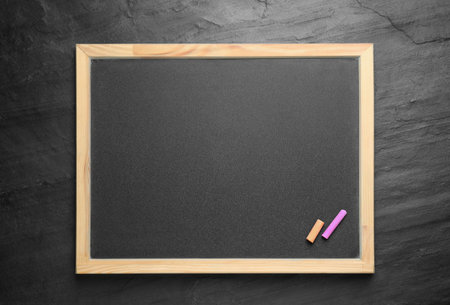 Empty blackboard with chalk on slate background, top view. Space for text