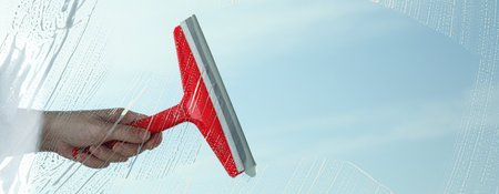 Woman cleaning window with squeegee on spring day, closeup view. banner designの写真素材