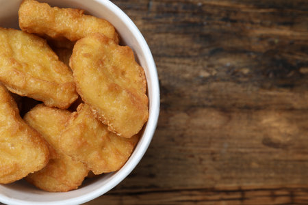 Bucket with tasty chicken nuggets on wooden table, top view. Space for textの写真素材