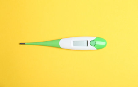 Modern digital thermometer on yellow background, top viewの写真素材