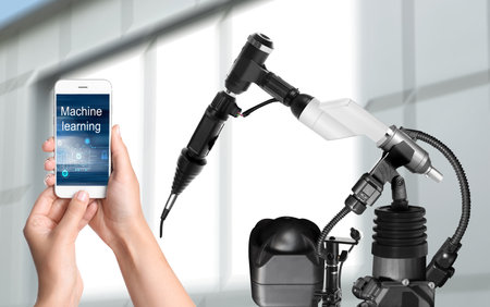 Engineer controlling electronic laboratory robot manipulator with smartphone indoors, closeup....
