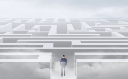 Young businessman in suit trying to find a way out of mazeの写真素材