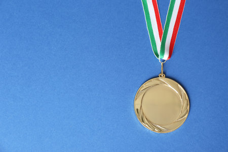 Gold medal on blue background, top view. Space for designの写真素材