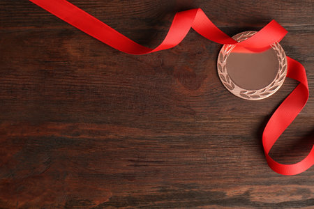 Bronze medal with red ribbon on wooden background, flat lay. Space for designの写真素材