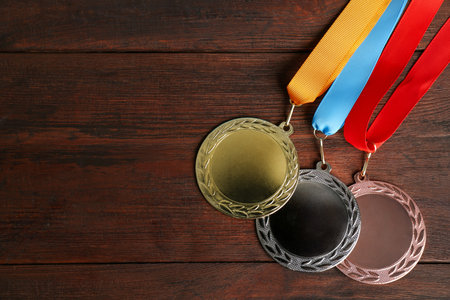 Gold, silver and bronze medals on wooden background, flat lay. Space for designの写真素材