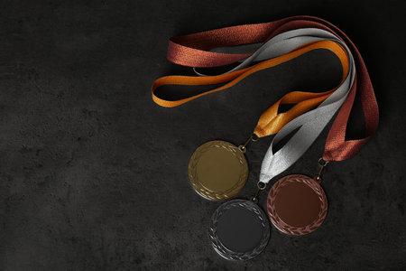 Gold, silver and bronze medals on gray stone background, flat lay. space for design